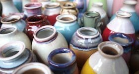 Intricate handmade ceramic jugs in a vibrant mix of colors and glazes, showcasing traditional pottery art.