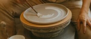 A potter skillfully creating a ceramic plate in a rustic workshop setting.