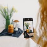 A person photographing a still life composition with a smartphone camera.